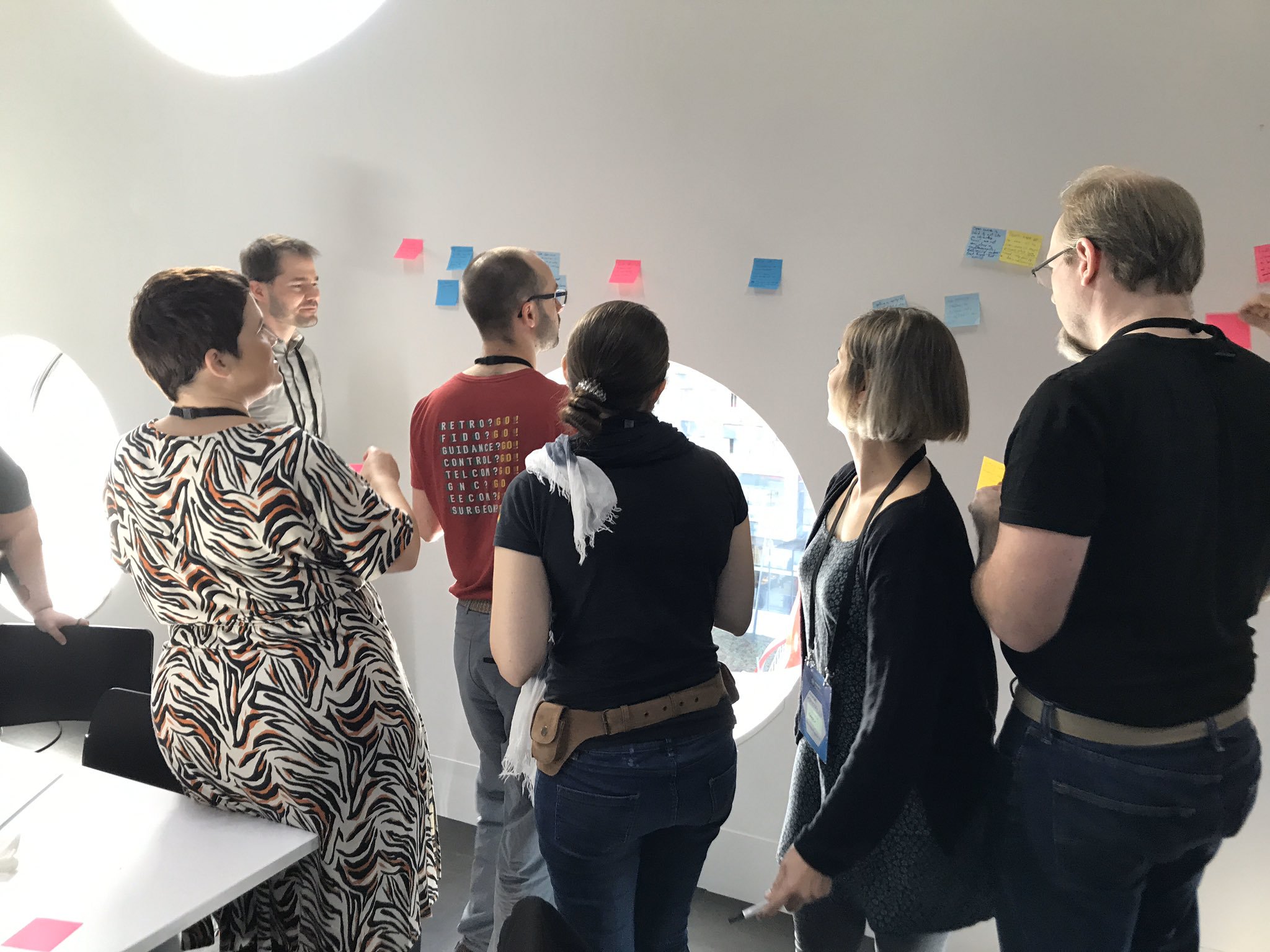 A group of people at #mozfest, clustered around a wall with post-it notes on